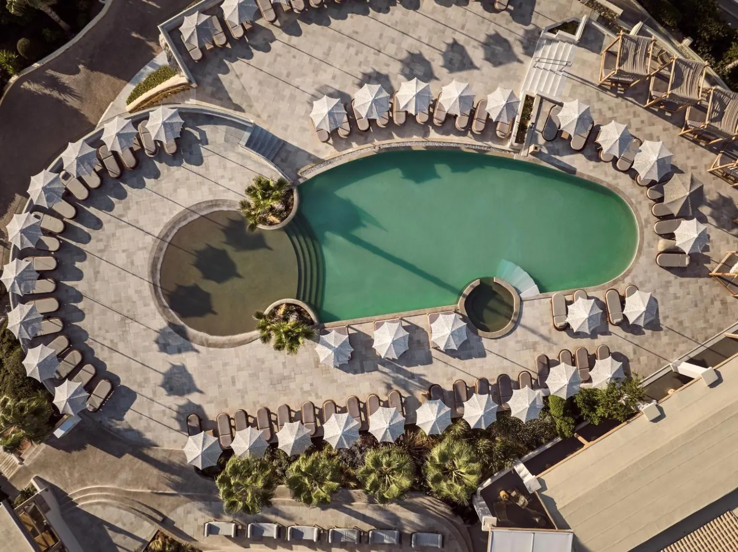 Aerial view of the curving outdoor pool ringed by sunbeds and parasols