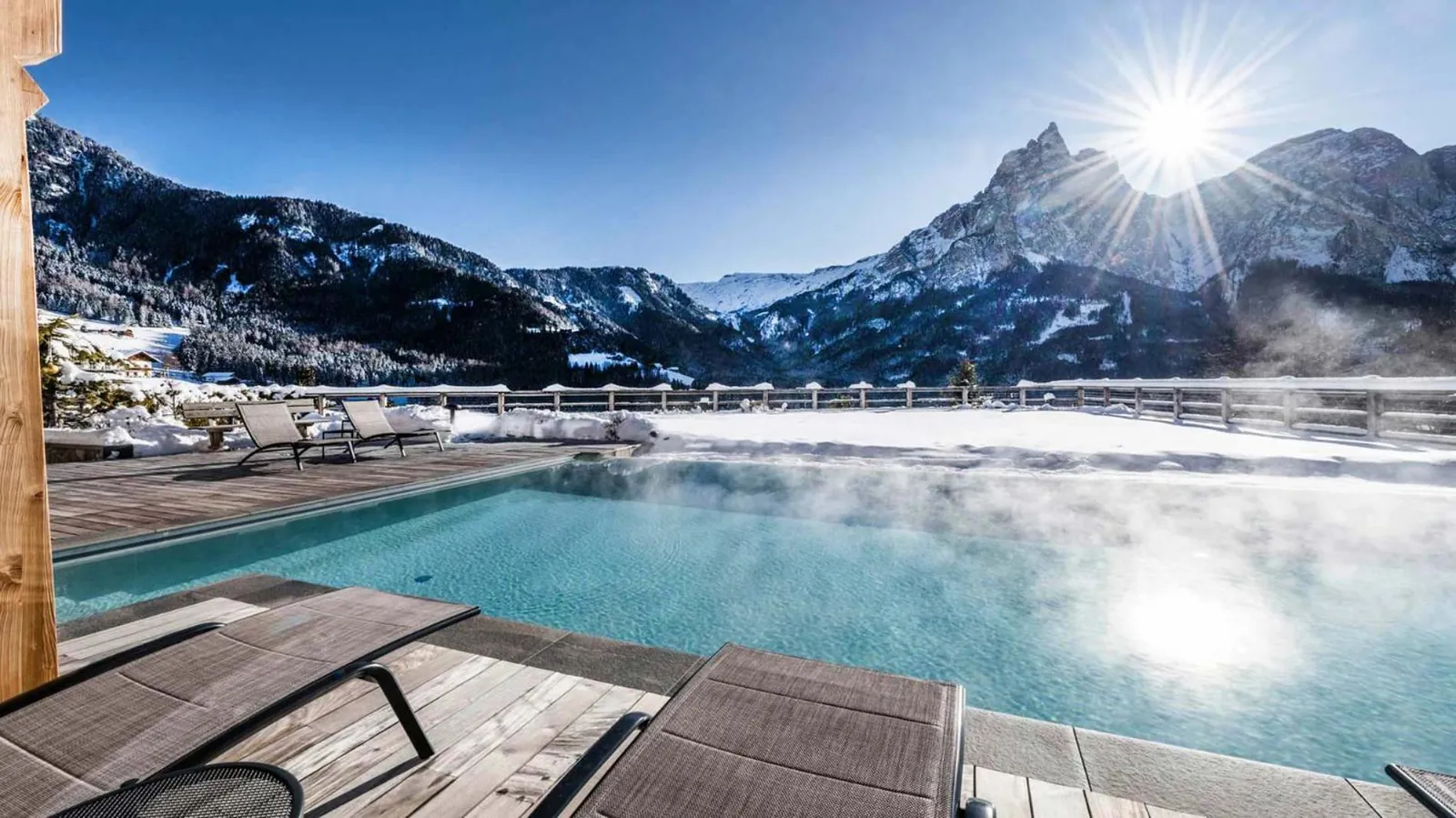 Steam rising off the heated outdoor pool at Sonus Alpis in winter, with the Sciliar behind