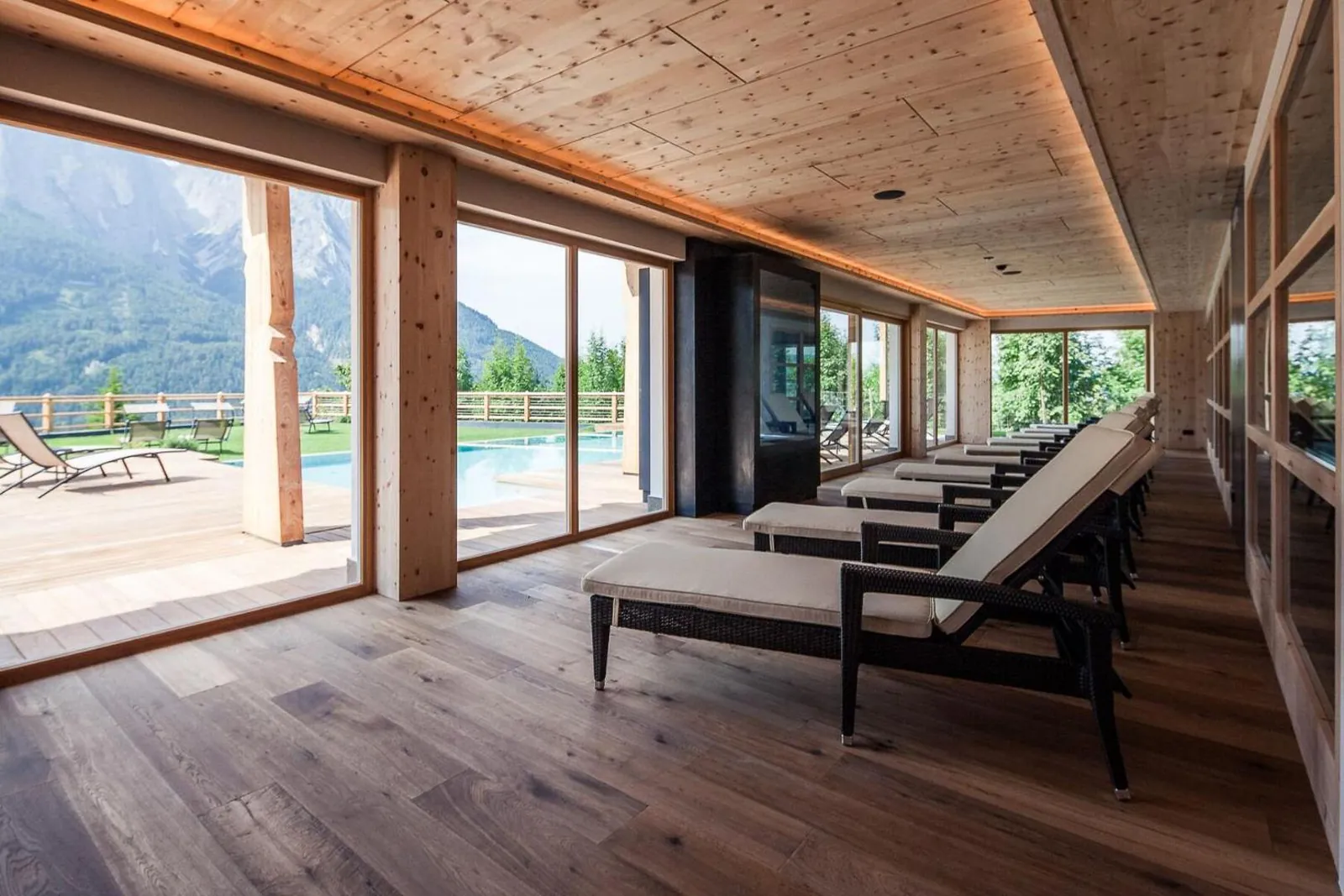 Relaxation room with loungers and glass walls facing the pool at Sonus Alpis