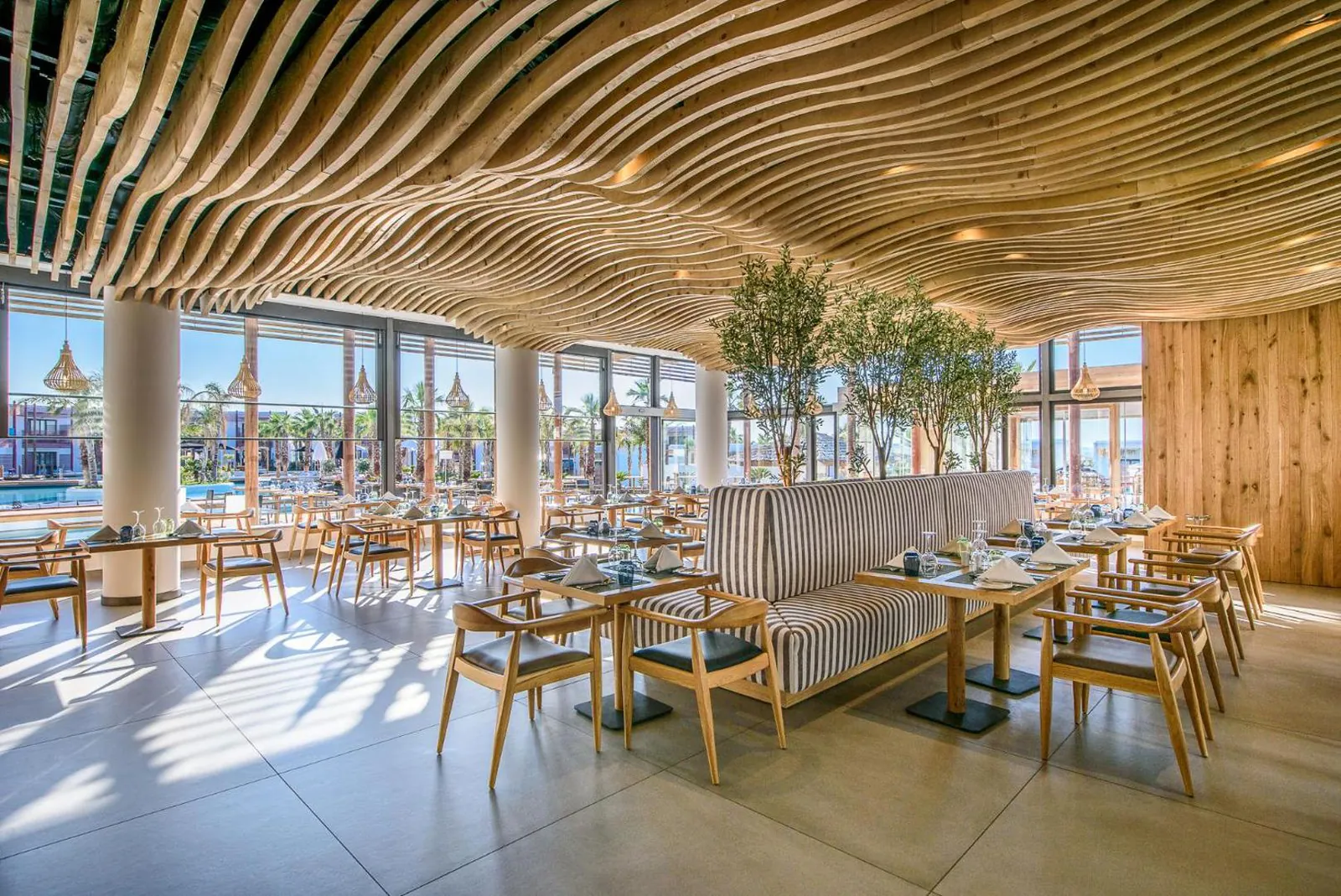 Restaurant with a wave-shaped wooden ceiling and pool views