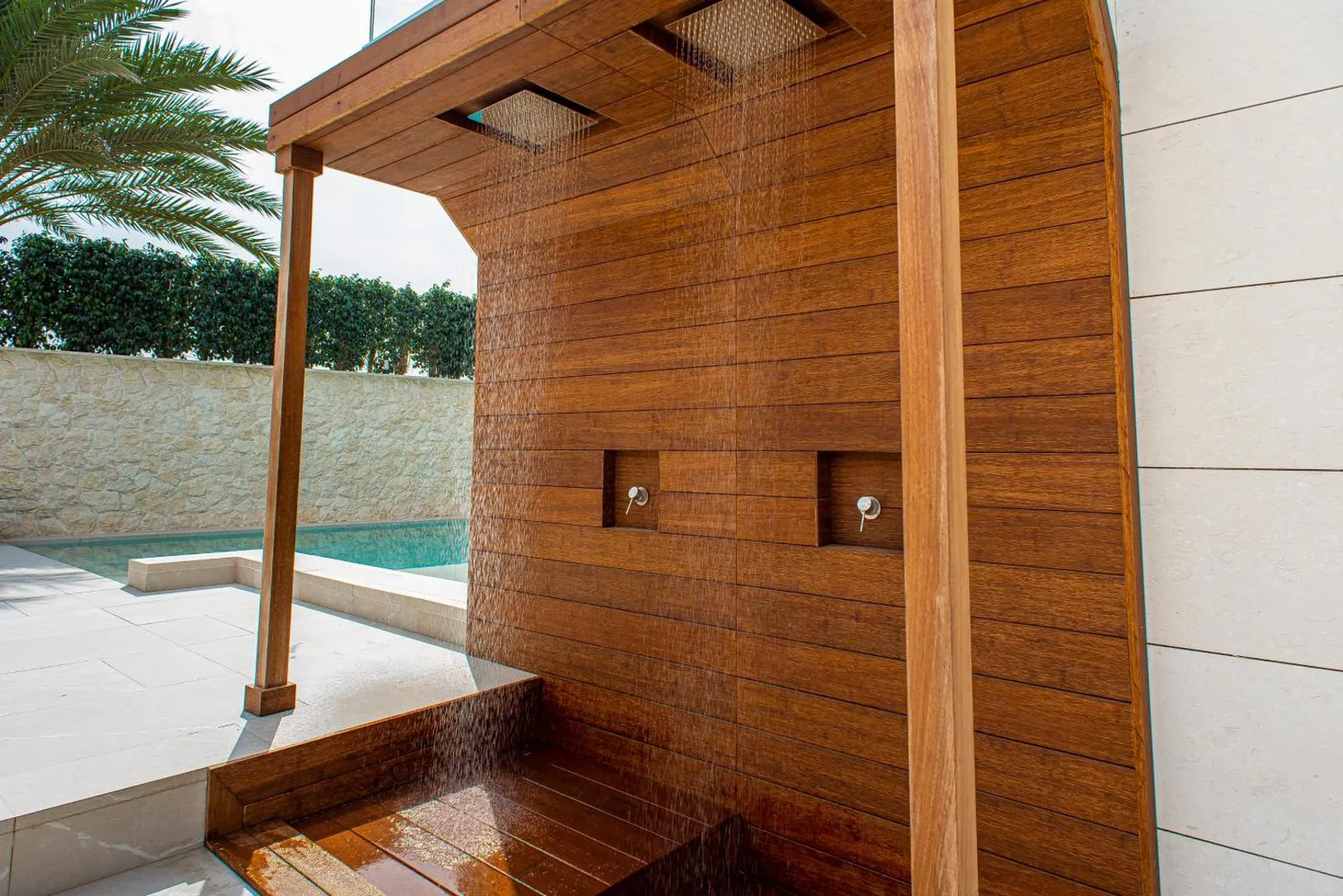 Outdoor rain shower in a timber alcove next to the pool