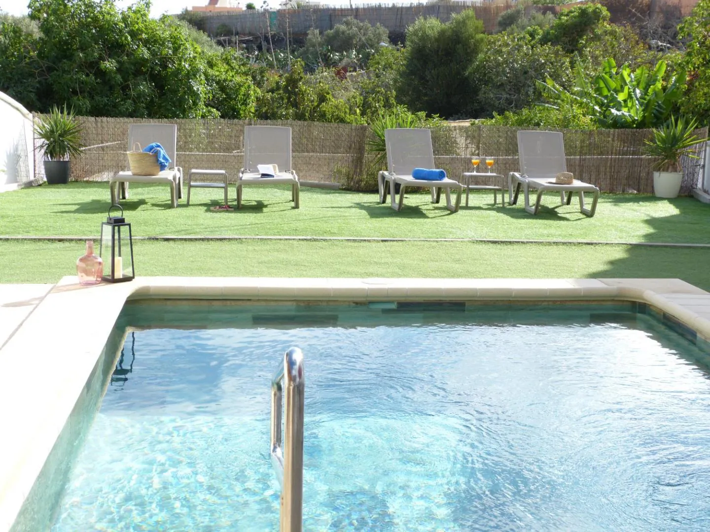 Private heated saltwater pool set into the lawn, with loungers along the garden fence