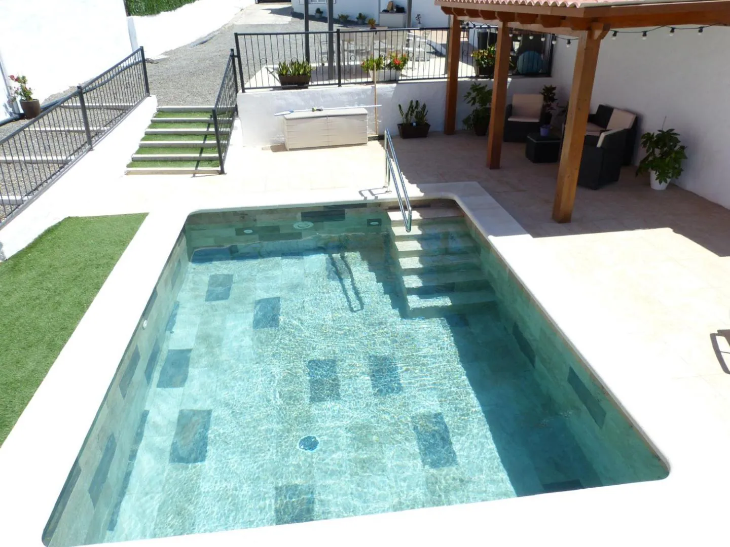 Steps leading into the pool beside the pergola-shaded terrace