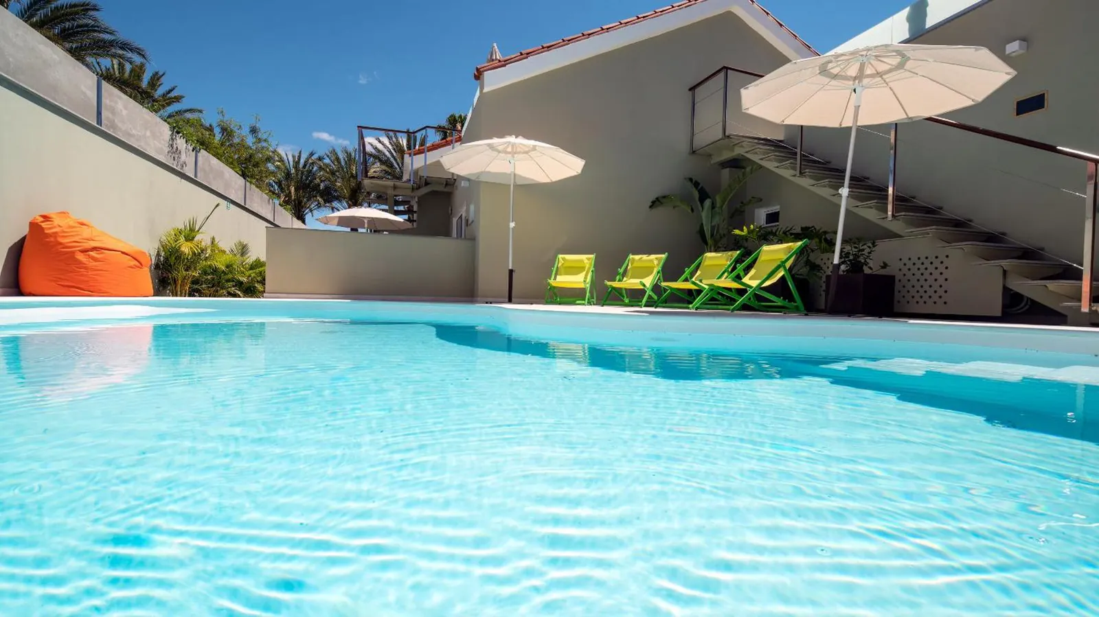 Clear water and steps into the pool, with the sun terrace and loungers behind