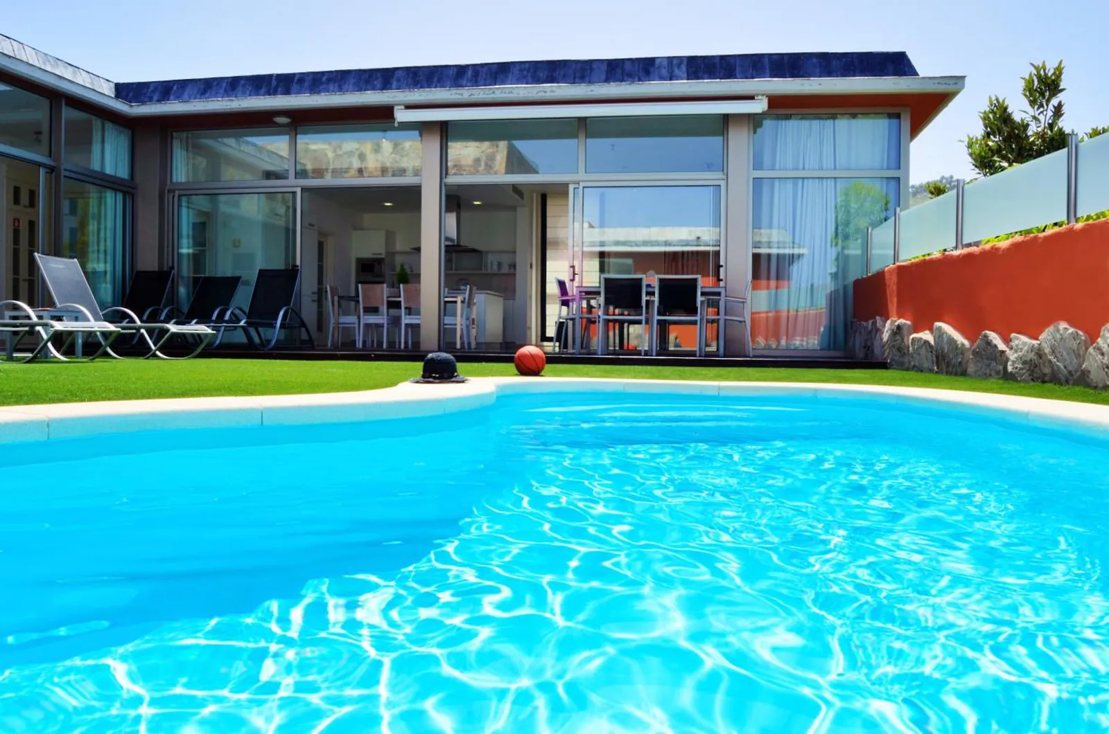Private pool on an artificial lawn in front of a glass-walled villa at Villas Opal Anfi Tauro