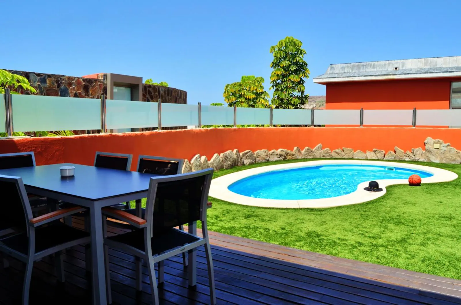 Outdoor dining table on a wooden deck beside the villa pool
