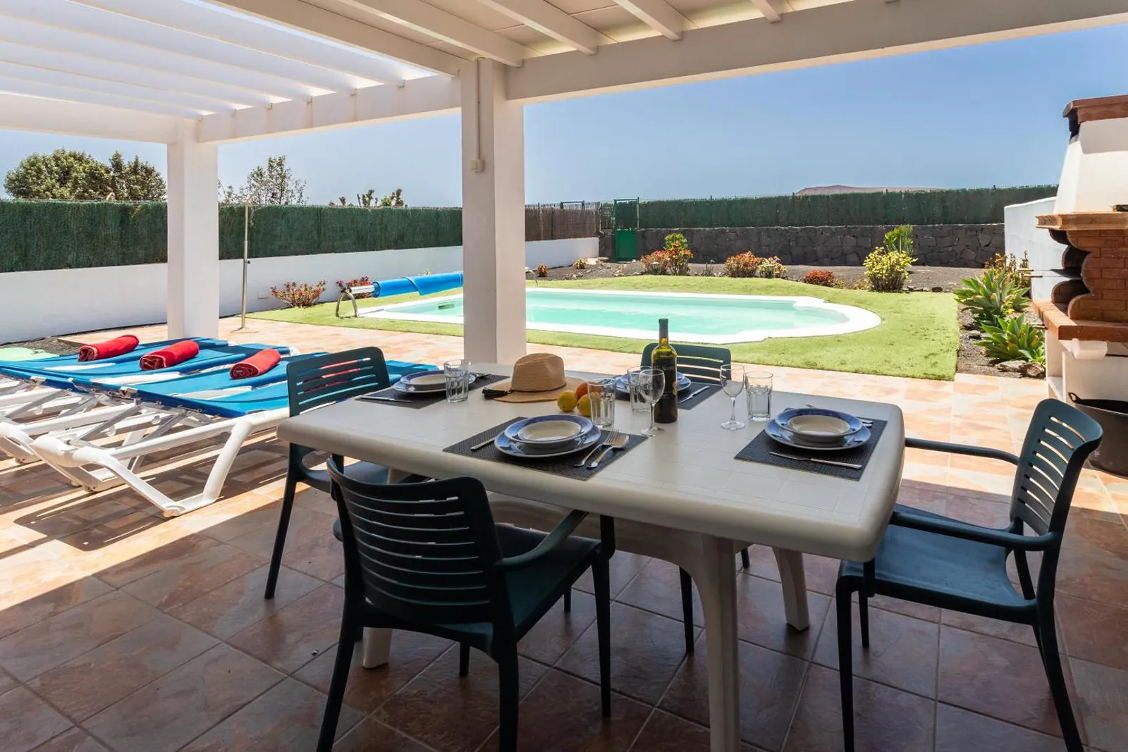 Pergola-shaded dining table on the terrace looking onto the pool