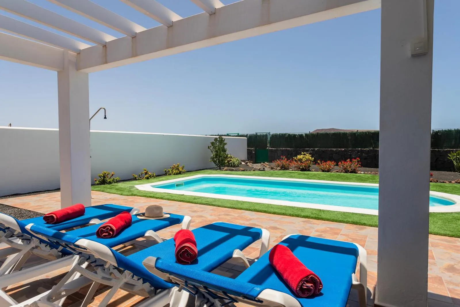 Blue loungers with towels lined up beside the pool under the pergola
