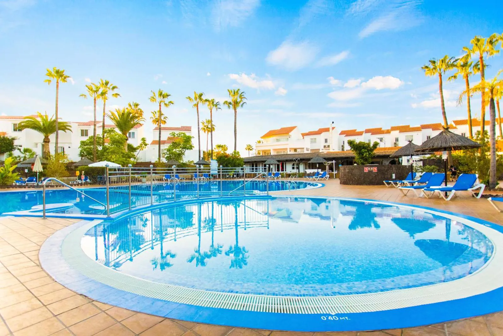 The heated main pool at Wyndham Residences Golf del Sur, curving between palms and the resort's white buildings